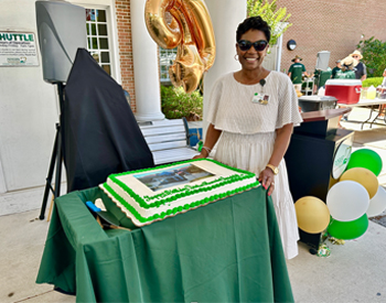 Dosher CEO Lynda Stanley stands beside a birthday cake for Dosher Hospital at the 2024 Community Cookout.