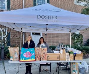 Dosher tent with table full of canned goods and 2 female staff